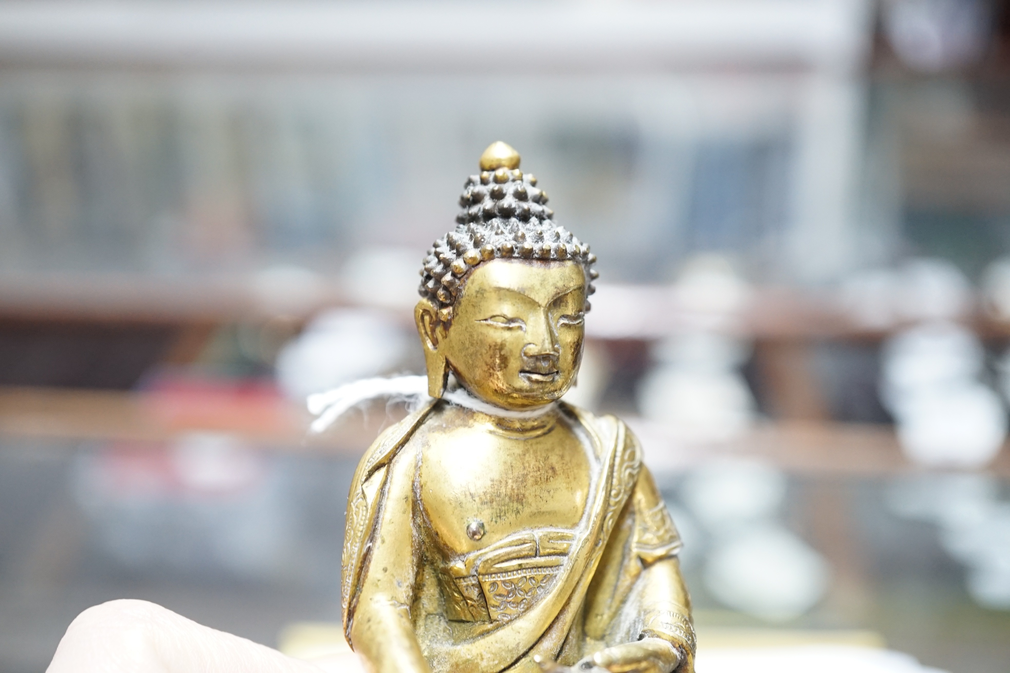 A small Tibetan gilt bronze seated figure of Buddha Shakyamuni, 18th century, 9.5cm high, lacking bowl in left hand
